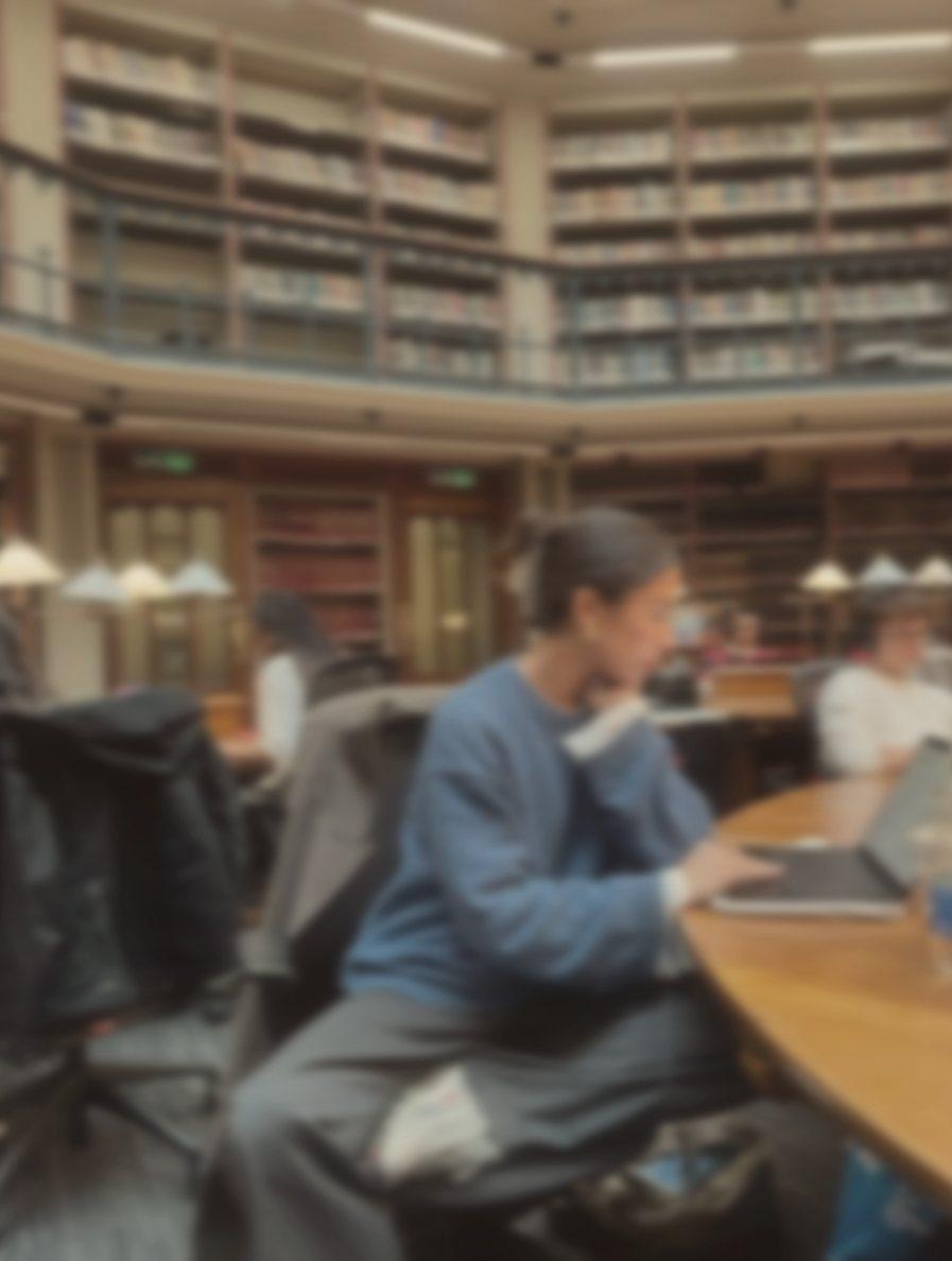 A student typing at a round table in a library